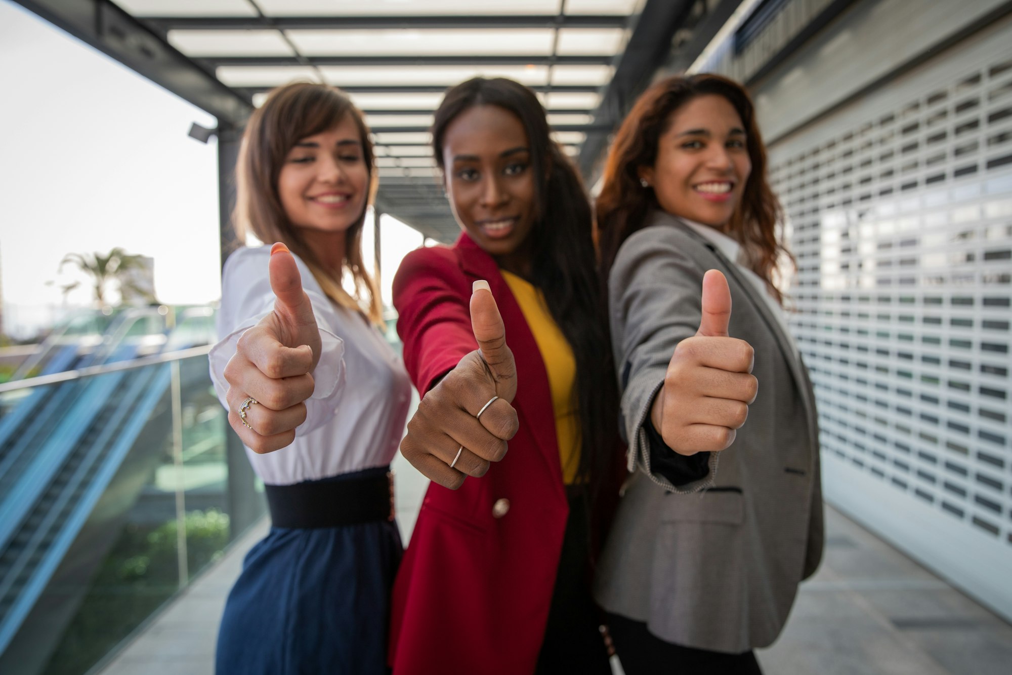 Three businesswomen with thumbs up, expression of satisfaction and approval.