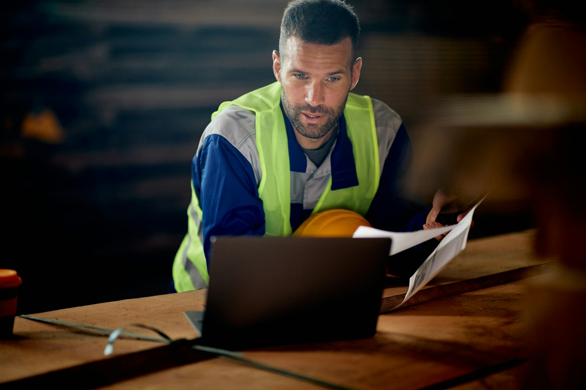 Warehouse foreman working on working on computer while analyzing reports at lumber department.